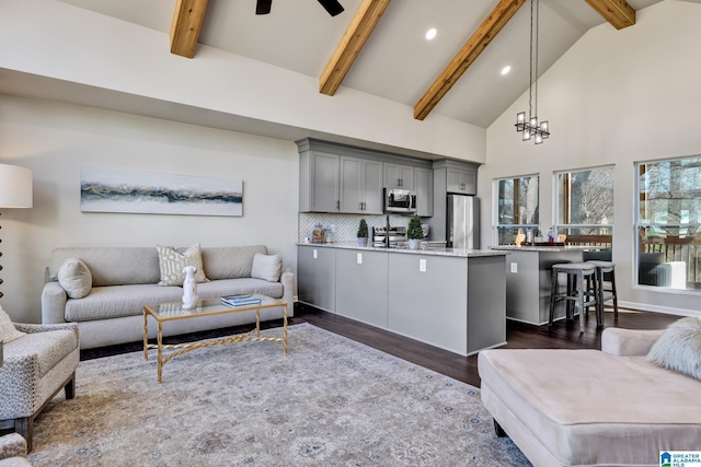 living room with beam ceiling, high vaulted ceiling, ceiling fan with notable chandelier, dark wood finished floors, and recessed lighting