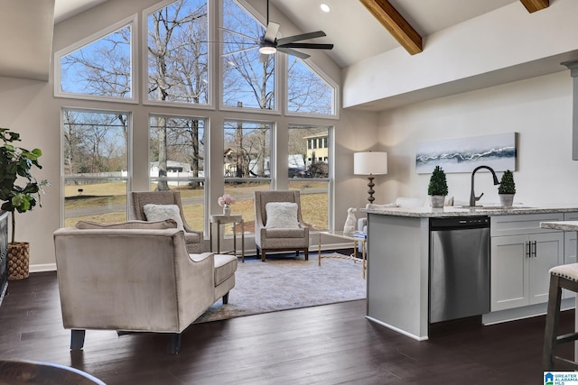 living room featuring dark wood-style floors, beamed ceiling, a ceiling fan, and a wealth of natural light