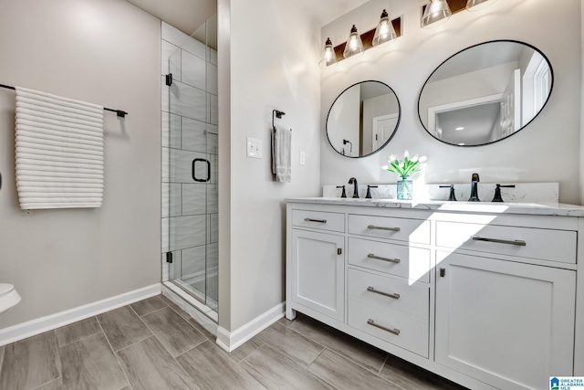 full bath featuring a sink, a shower stall, baseboards, and double vanity