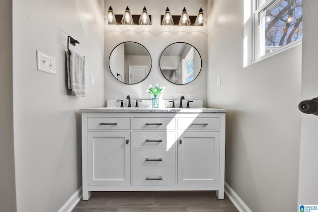 full bathroom featuring a sink, baseboards, and double vanity