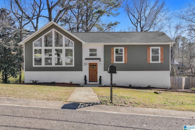 view of front of property with brick siding, a front lawn, and fence