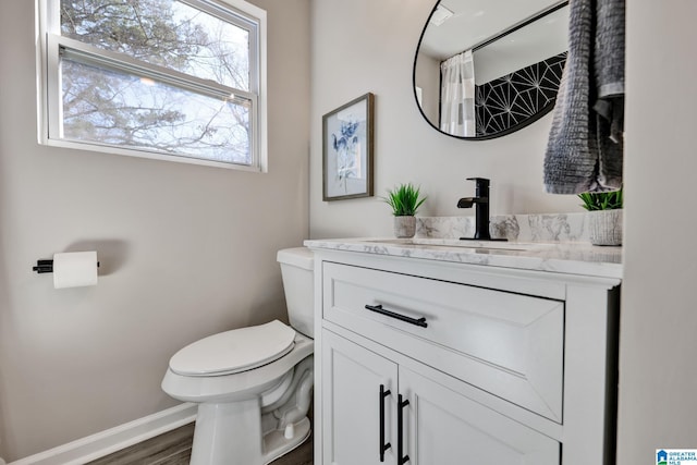 full bath with vanity, toilet, wood finished floors, and baseboards