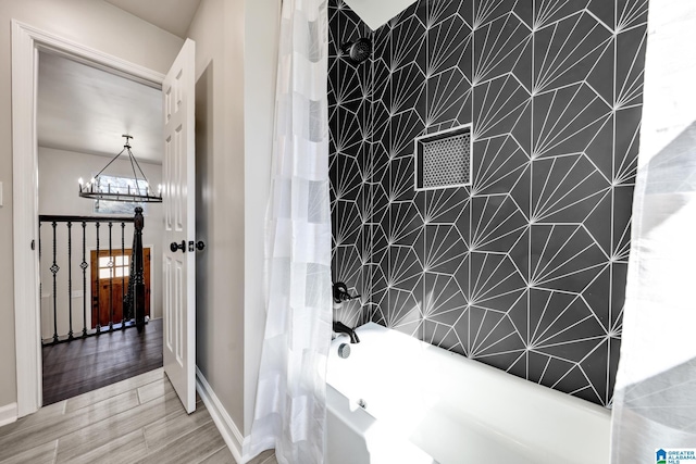 full bathroom with wood tiled floor, an inviting chandelier, and shower / bath combo