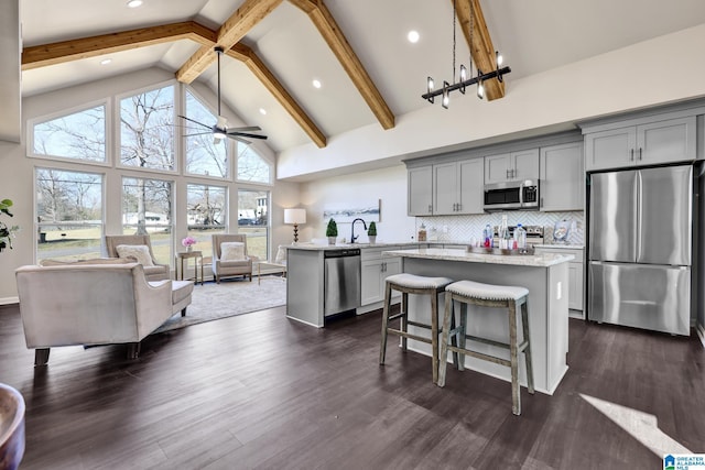 kitchen featuring high vaulted ceiling, a kitchen island, gray cabinetry, appliances with stainless steel finishes, and tasteful backsplash