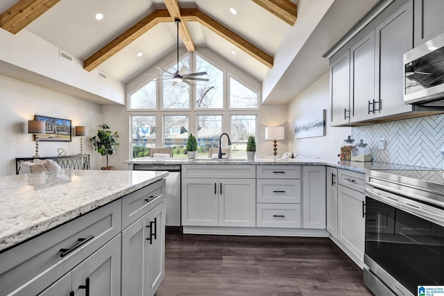 kitchen with beam ceiling, plenty of natural light, appliances with stainless steel finishes, and a sink