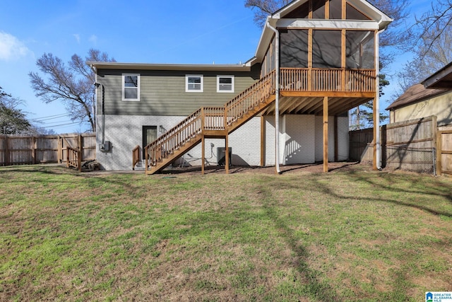 back of house featuring stairway, a yard, brick siding, and a sunroom