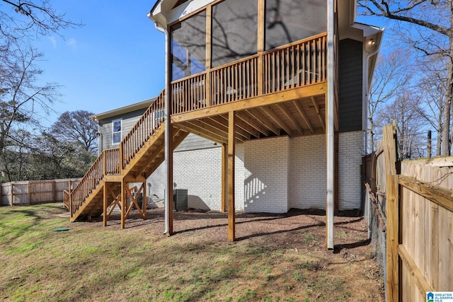 exterior space featuring fence, a wooden deck, stairs, a lawn, and brick siding