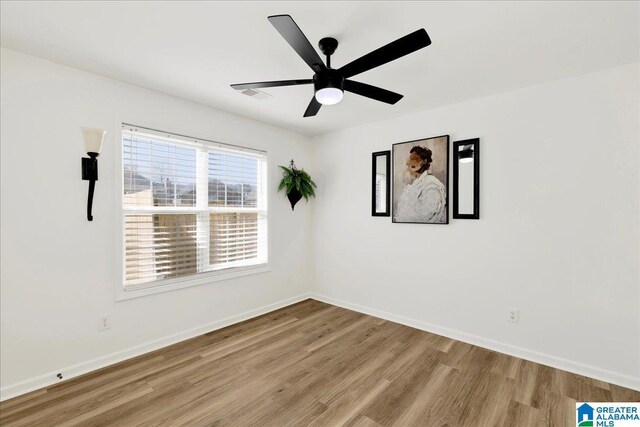 unfurnished room featuring a ceiling fan, visible vents, wood finished floors, and baseboards