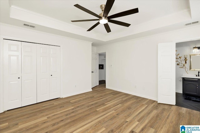 unfurnished bedroom with a tray ceiling and visible vents