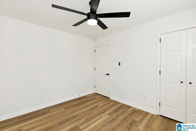 unfurnished bedroom with a closet, baseboards, light wood-style flooring, and a ceiling fan