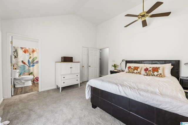 carpeted bedroom with ensuite bath, a ceiling fan, baseboards, and high vaulted ceiling