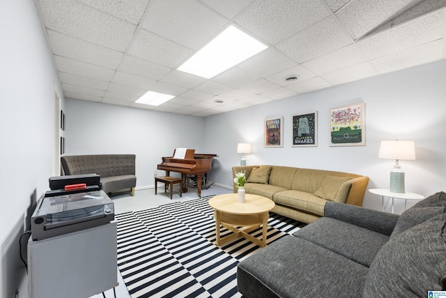 carpeted living room with visible vents, baseboards, and a drop ceiling