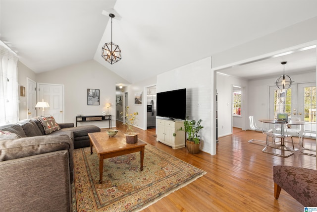 living room featuring lofted ceiling, a notable chandelier, and light wood finished floors