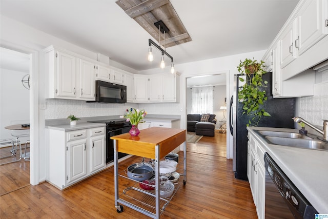 kitchen with light wood-type flooring, black appliances, a sink, white cabinets, and light countertops