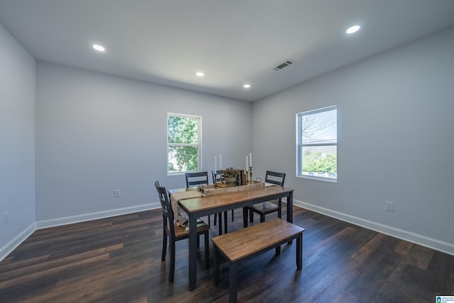 dining area with dark wood finished floors, baseboards, visible vents, and a wealth of natural light