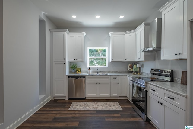 kitchen with dark wood finished floors, a sink, stainless steel appliances, white cabinetry, and wall chimney range hood