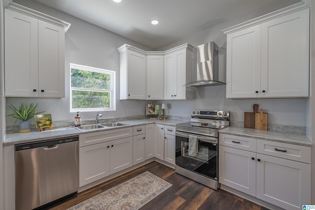 kitchen with a sink, wall chimney range hood, white cabinetry, stainless steel appliances, and light countertops