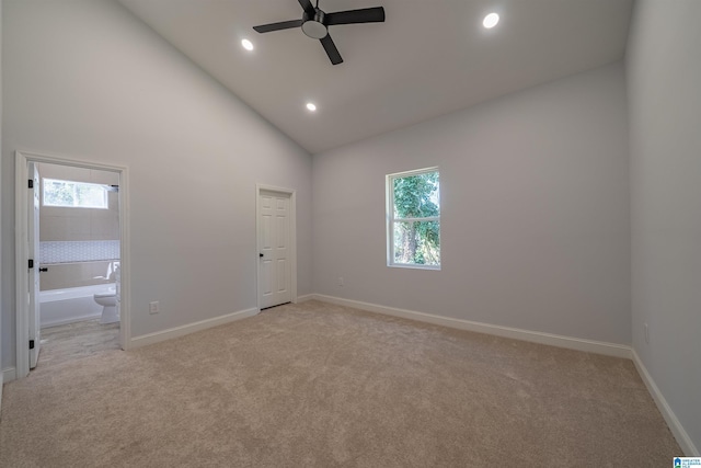 interior space featuring recessed lighting, light colored carpet, high vaulted ceiling, and baseboards