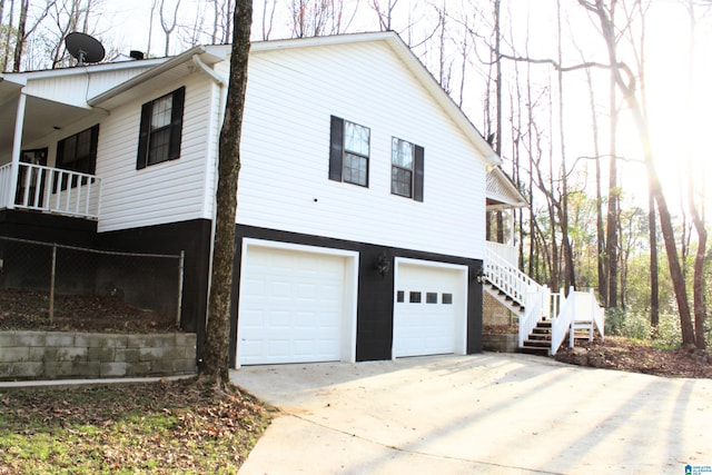 view of side of property featuring stairs, an attached garage, and driveway