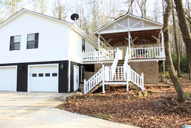 view of side of property featuring stairs, concrete driveway, a deck, and a garage