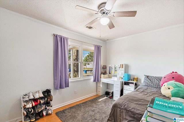 bedroom with visible vents, ornamental molding, a textured ceiling, and wood finished floors