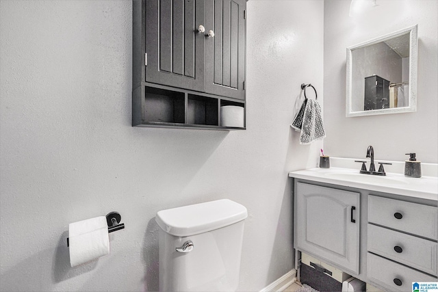 bathroom with baseboards, toilet, and vanity