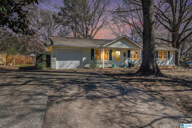 ranch-style house with an attached garage, fence, and driveway