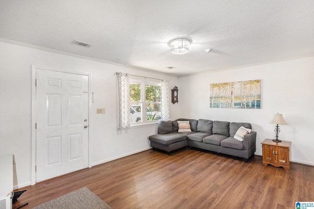 living room featuring baseboards, a textured ceiling, wood finished floors, and ornamental molding