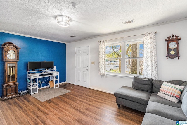 living area featuring visible vents, crown molding, baseboards, wood finished floors, and a textured ceiling