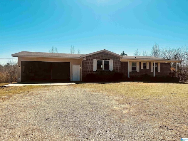 single story home featuring brick siding, driveway, a front yard, and an attached garage