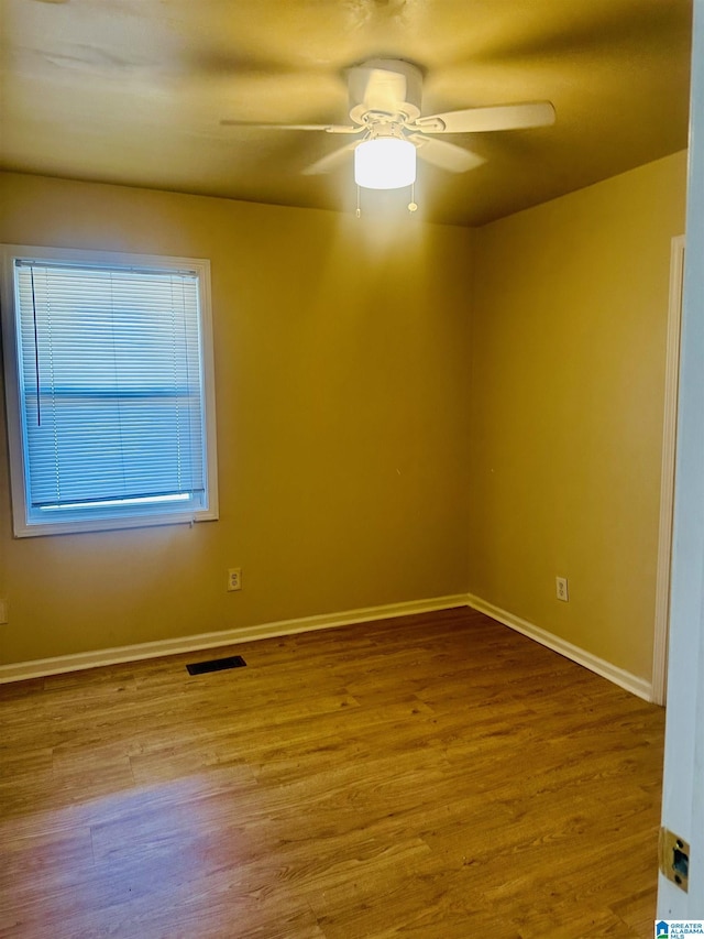empty room featuring visible vents, baseboards, wood finished floors, and a ceiling fan