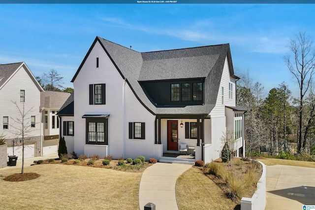 view of front facade featuring brick siding, a front lawn, and a shingled roof