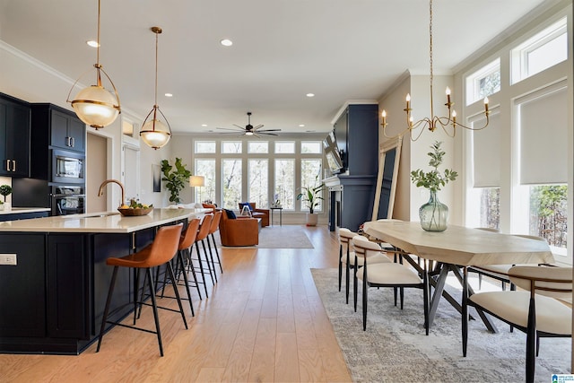 kitchen with ornamental molding, a sink, stainless steel microwave, wall oven, and light countertops