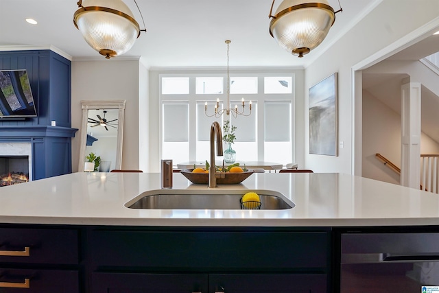 kitchen with a sink, a lit fireplace, a chandelier, and light countertops