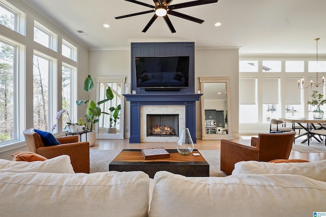 living room featuring ceiling fan with notable chandelier, visible vents, a wealth of natural light, and ornamental molding