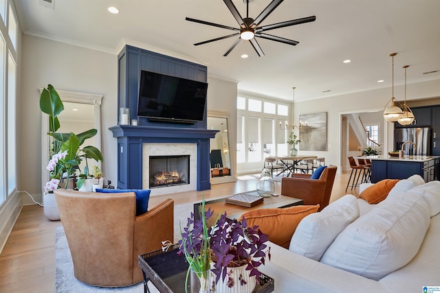 living room featuring crown molding, recessed lighting, light wood-style floors, and a premium fireplace