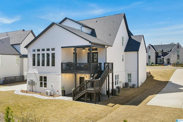 rear view of property featuring stairway, central AC unit, and a lawn