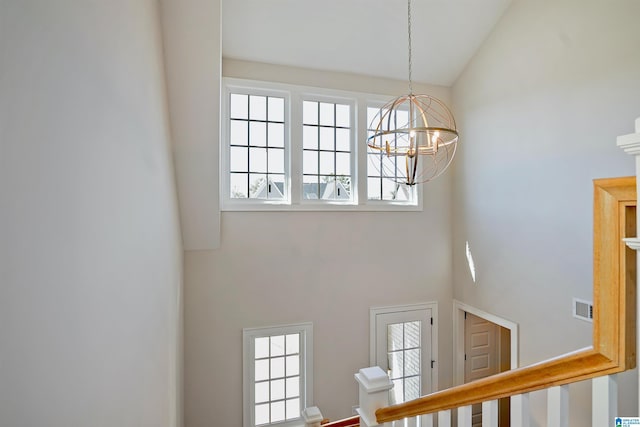 stairs featuring a notable chandelier, visible vents, and high vaulted ceiling