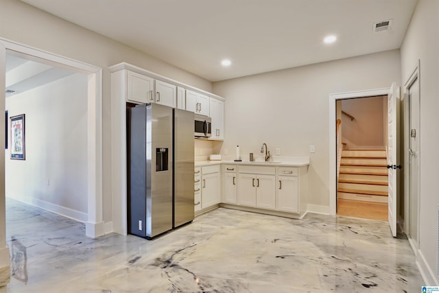 kitchen with visible vents, a sink, appliances with stainless steel finishes, white cabinets, and light countertops