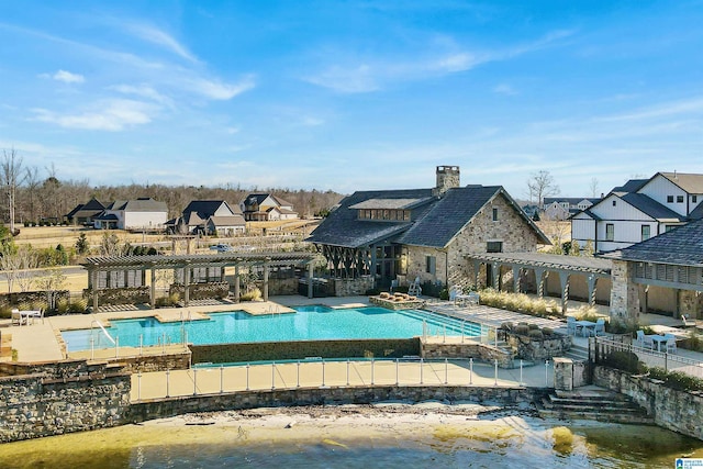 community pool with a jacuzzi, a patio area, a pergola, and a residential view