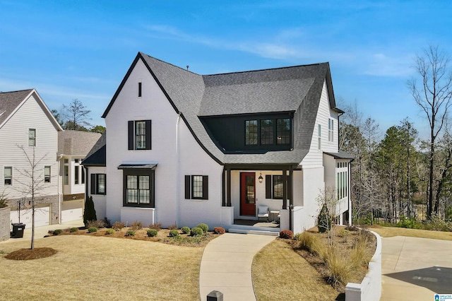 modern inspired farmhouse with brick siding, a front yard, and roof with shingles