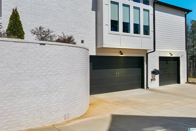 view of side of property featuring brick siding, concrete driveway, and a garage