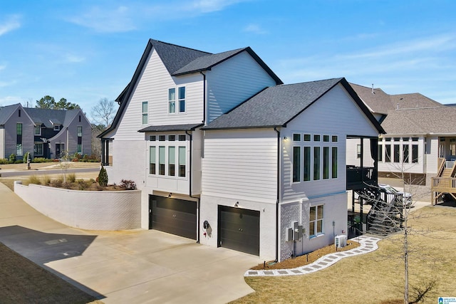 view of side of property featuring a shingled roof, a residential view, concrete driveway, cooling unit, and a garage