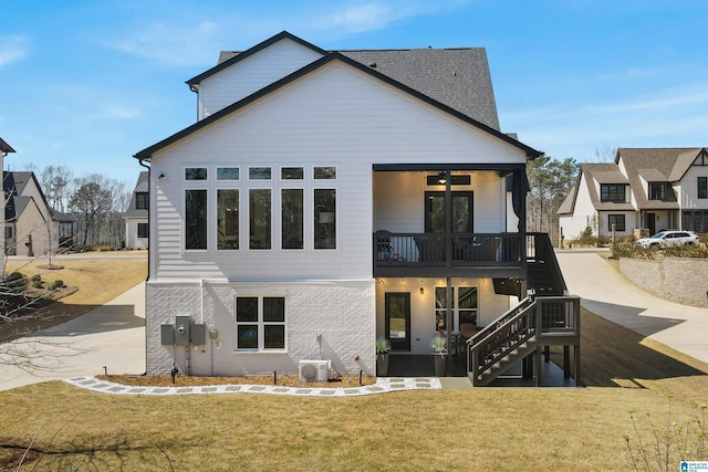 back of property featuring stairway, driveway, a yard, ac unit, and brick siding