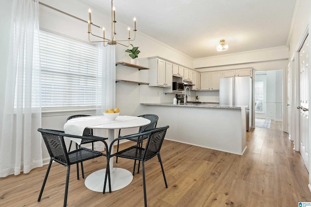 dining area featuring light wood-type flooring, a notable chandelier, and ornamental molding