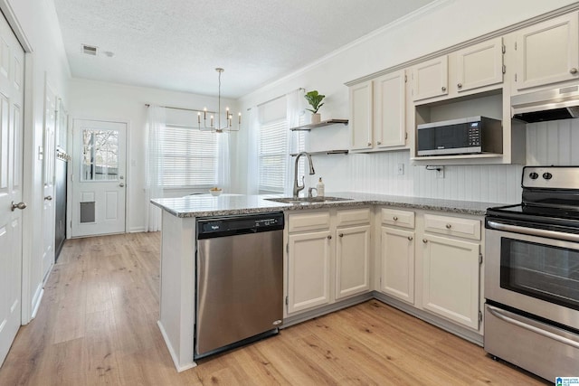 kitchen with a notable chandelier, under cabinet range hood, open shelves, a sink, and stainless steel appliances