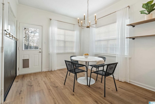 dining area featuring light wood-type flooring, baseboards, a chandelier, and crown molding