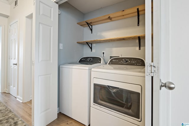 laundry room featuring light wood finished floors, laundry area, washing machine and dryer, and visible vents