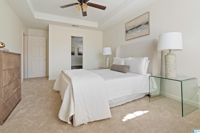 bedroom featuring carpet, visible vents, baseboards, ceiling fan, and a raised ceiling