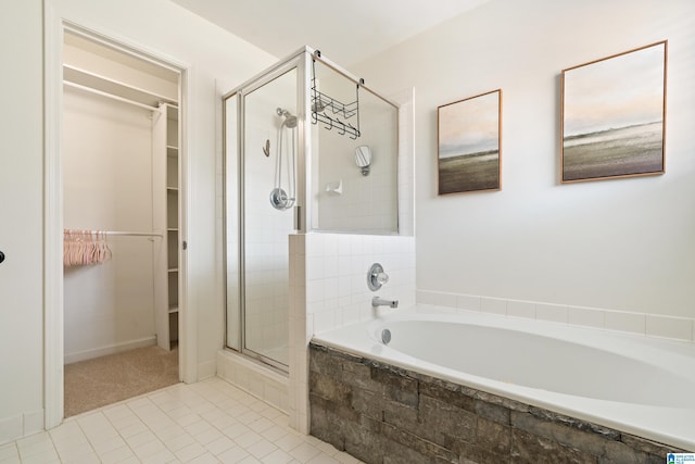 bathroom featuring a walk in closet, a shower stall, a garden tub, and tile patterned flooring